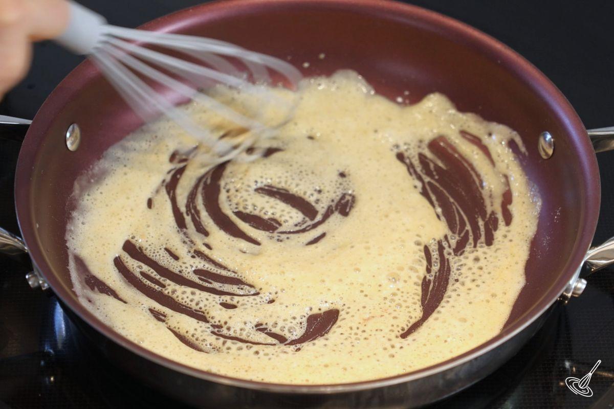 Someone whisking a roux in a large saucepan. 