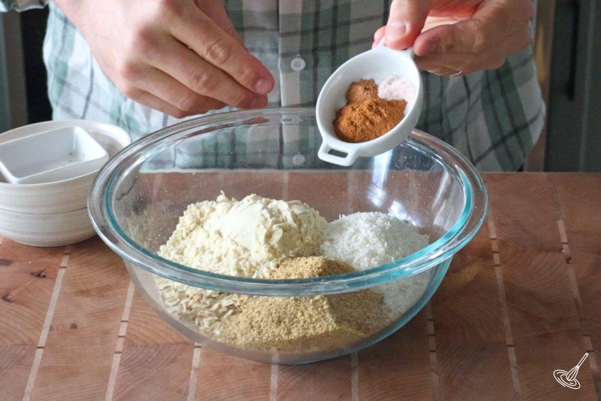 Someone adding cinnamon to a bowl of oats.