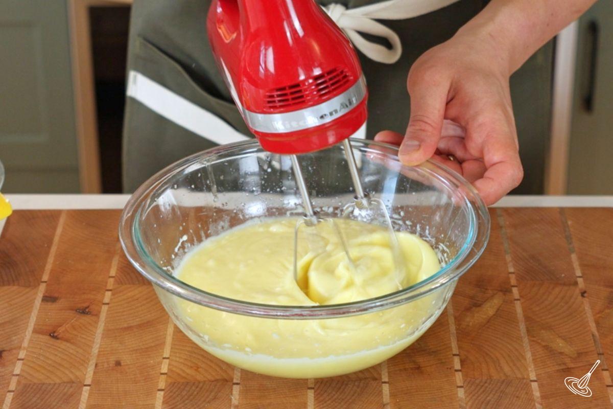 Someone using a hand blender to mix a cake batter.