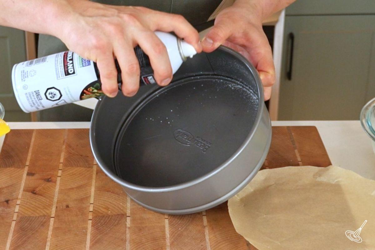 Someone spraying nonstick spray in a springform pan.