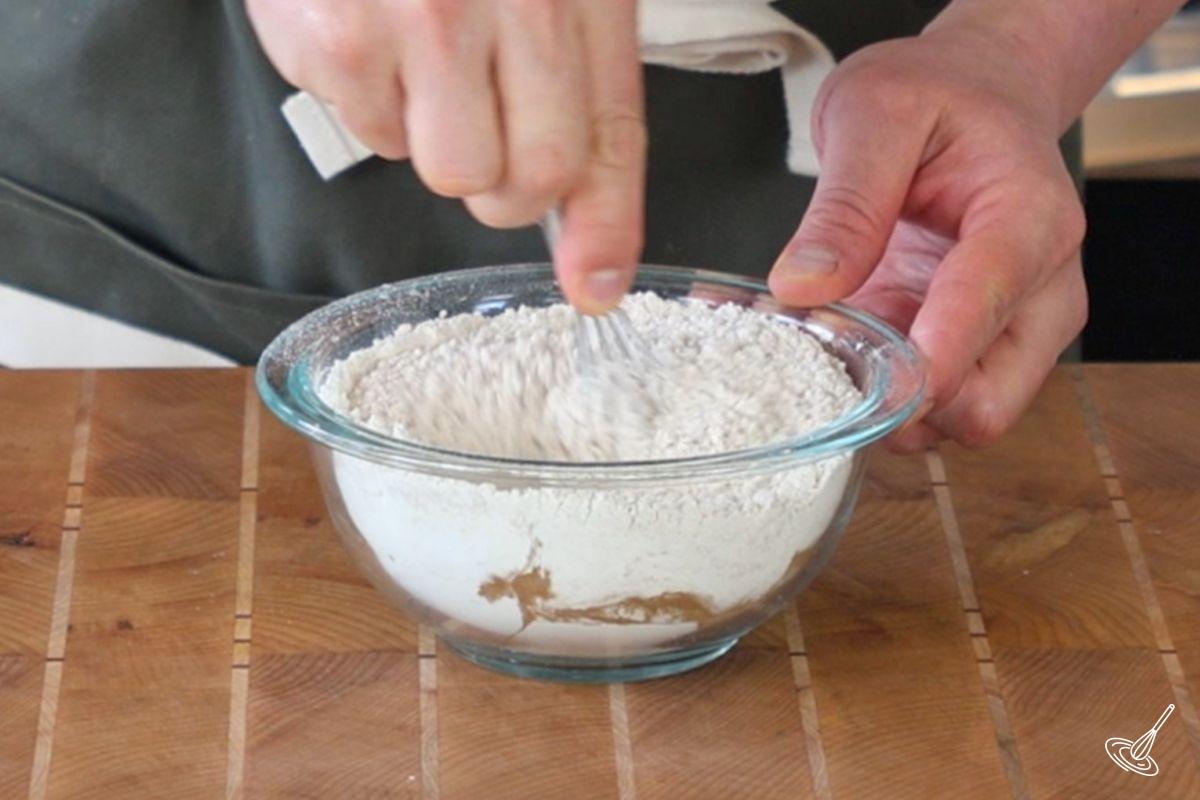 Someone whisking together a small bowl of flour.