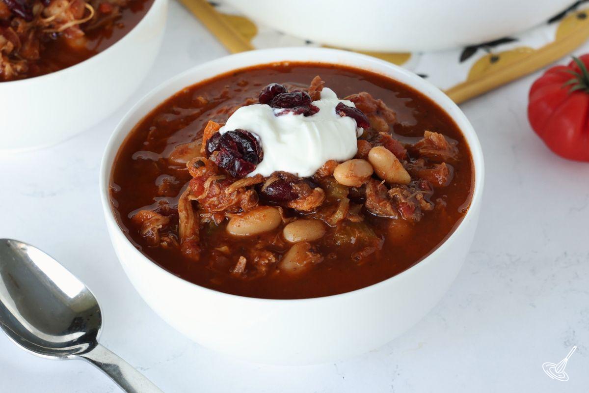 A bowl of cranberry turkey chili on a kitchen counter. 