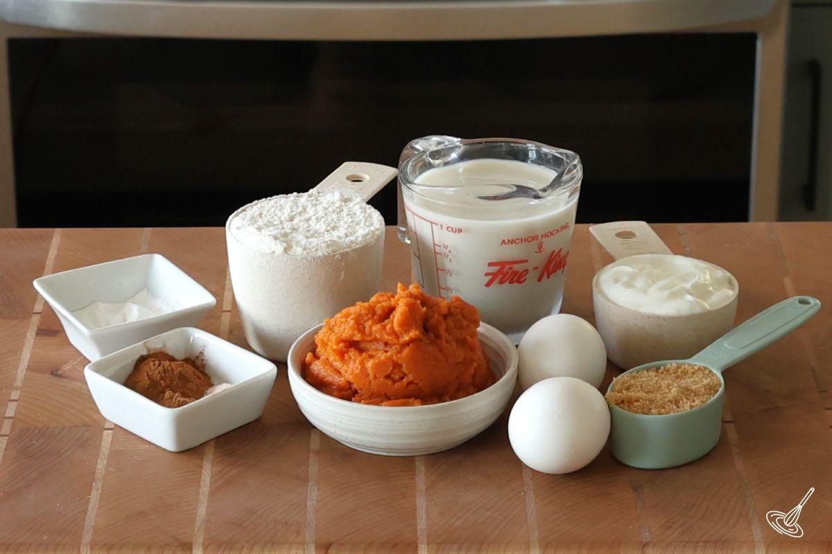 Ingredients to make pumpkin pancakes, including greek yogurt, milk, and eggs.