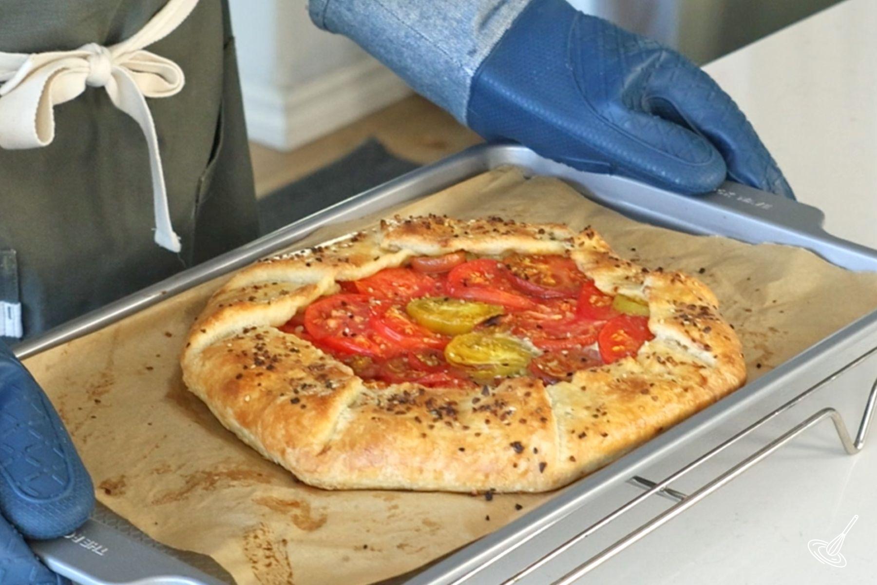 Quelqu’un plaçant la galette à la tomate et au pesto cuite sur une grille de refroidissement.