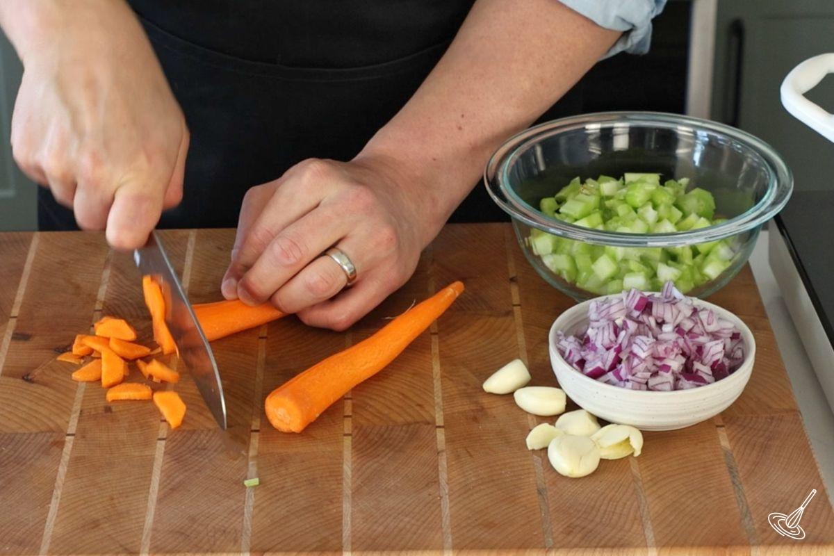 Someone cutting a carrot into small pieces. 