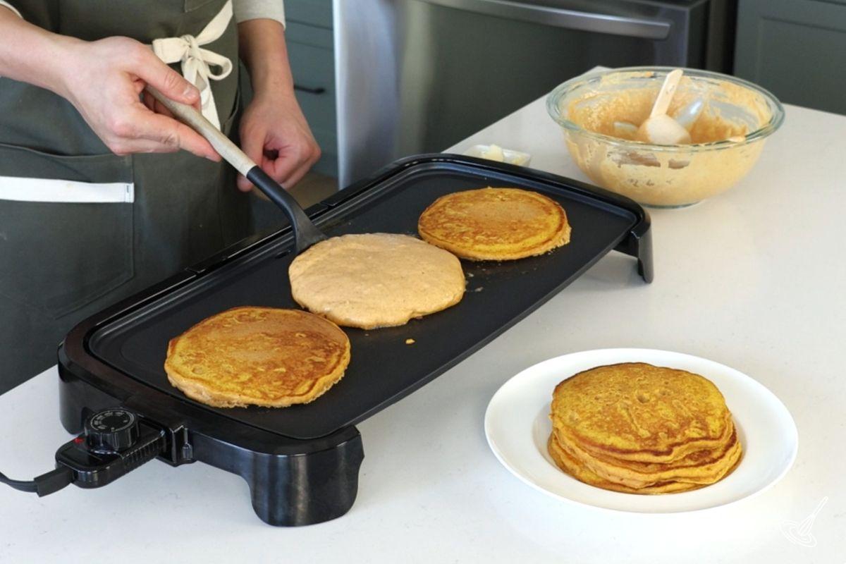 Someone flipping pumpkin greek yogurt pancake on a griddle. 