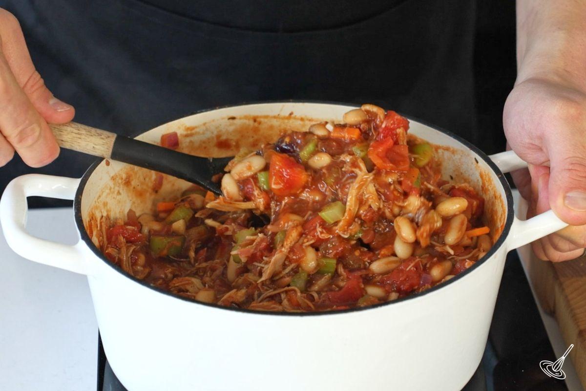 Someone stirring a cooked cranberry turkey chili.