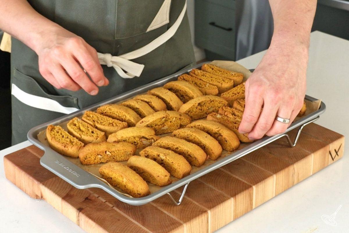 Someone flipping baked biscotti on the tray as they cool. 
