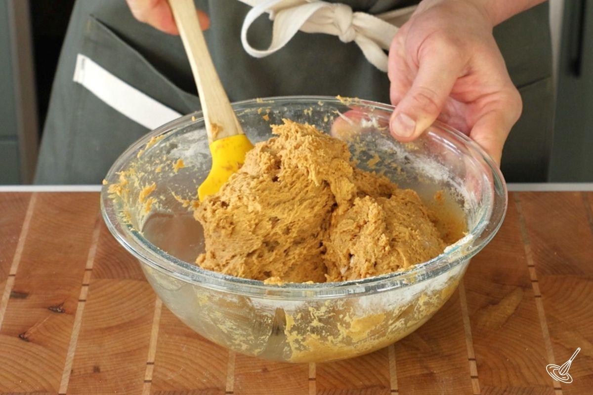 Someone using a rubber spatula to mix biscotti dough.