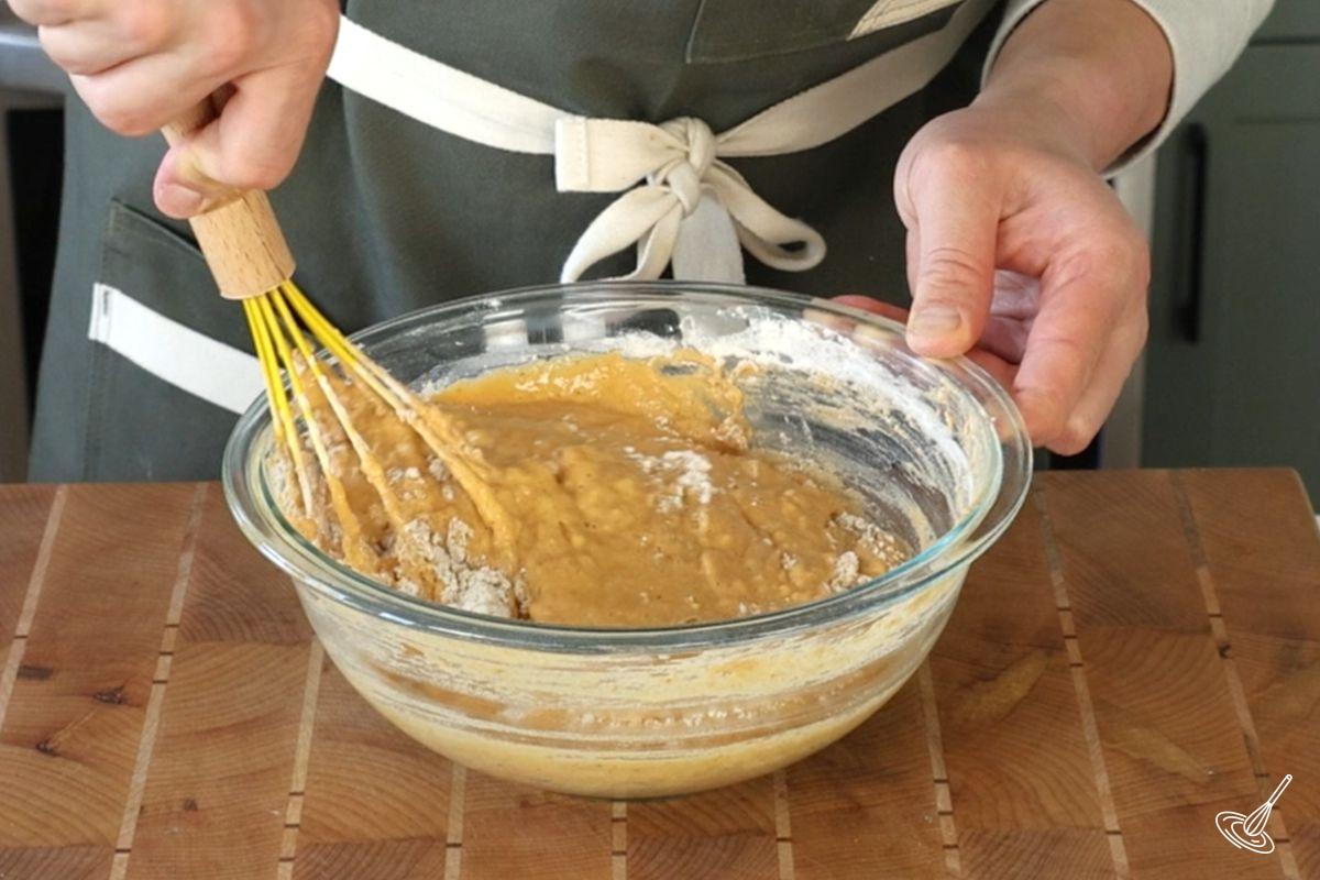 Someone using a whisk to mix together pancake batter.