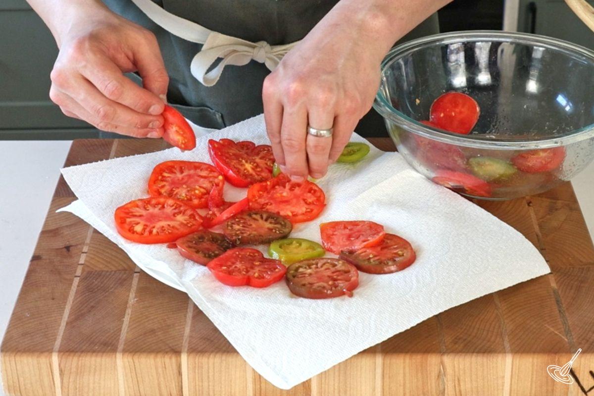 Des tranches de tomates déposées sur du papier absorbant pour les faire sécher.