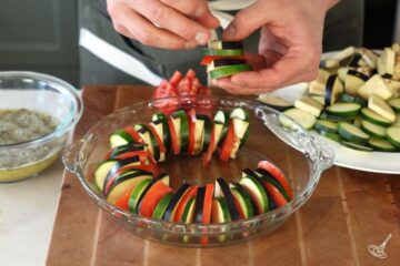 arranging slices of vegetables in a baking dish.