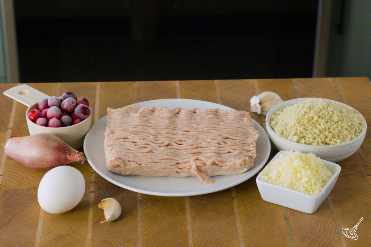 Ingredients on a cutting board, including a plate of ground turkey meat.