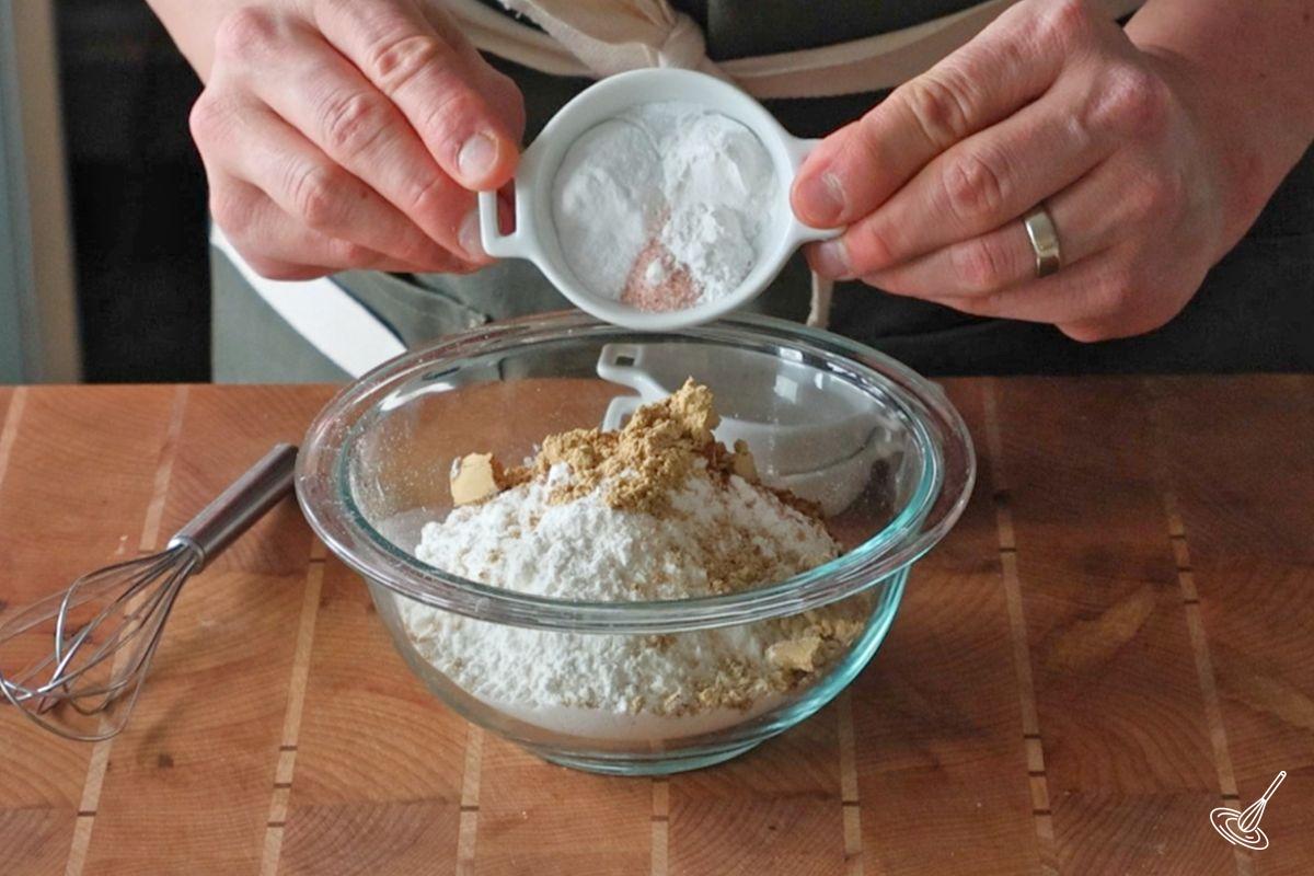 Someone combining dry ingredients in a bowl.
