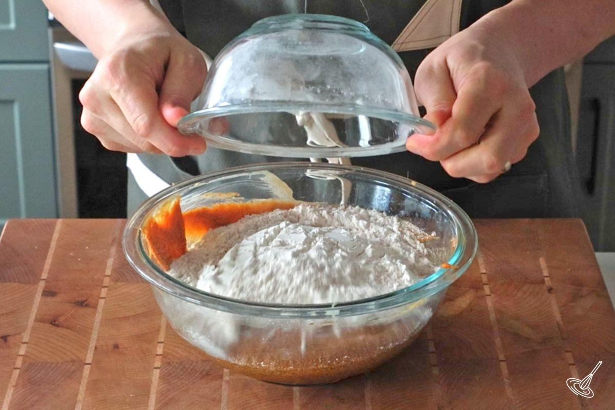 Someone adding a bowl of dry ingredients into a bowl of wet ingredients. 