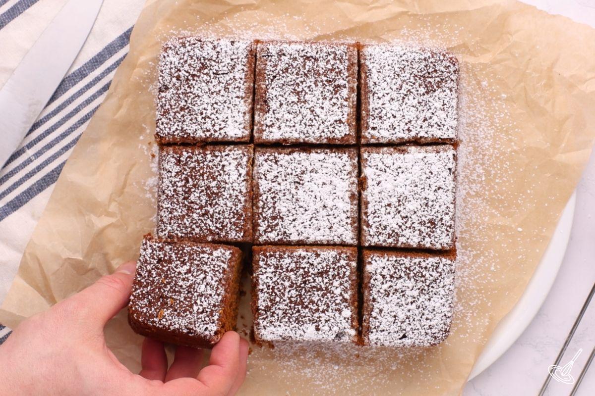 Someone taking a square of pumpkin gingerbread snack cake.