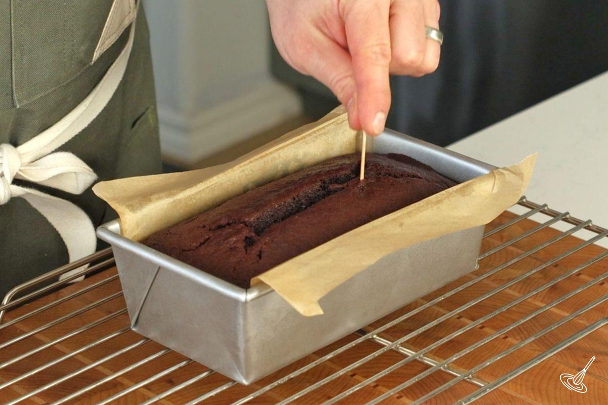 Someone using a toothpick to test the doneness of the loaf.