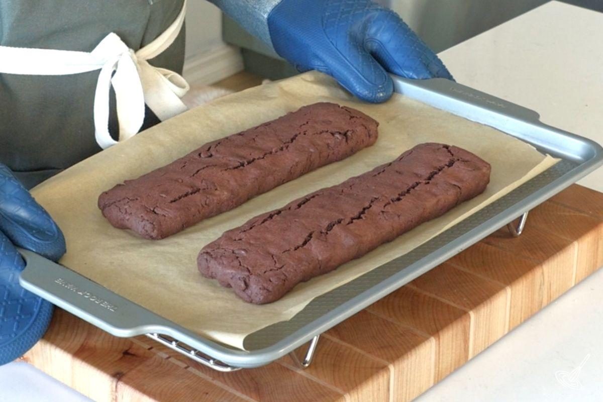 Baked chocolate peppermint biscotti logs on a baking tray. 