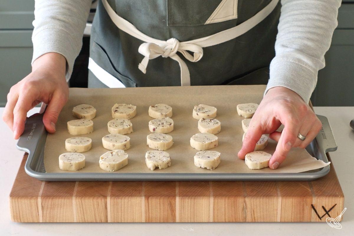 Someone placing shortbread cookies on a baking tray. 