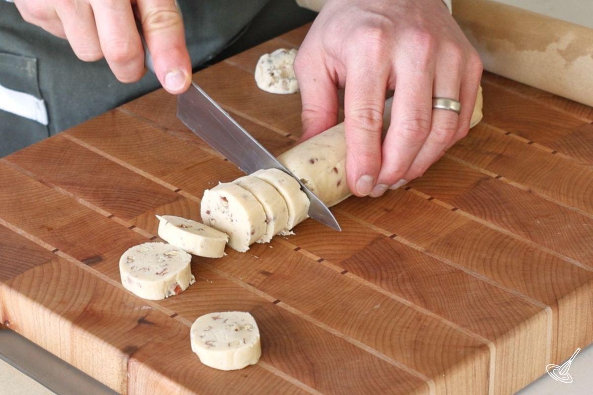 Someone using a knife to cut out maple pecan shortbread cookies.