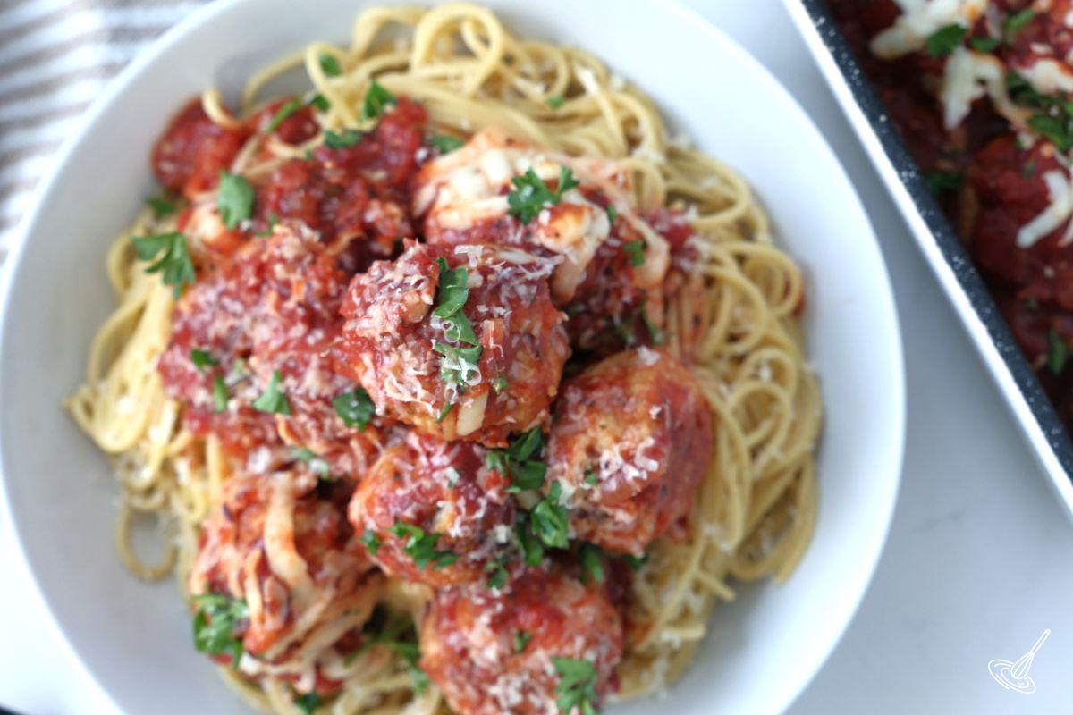 Chicken Parm Meatballs over spaghetti in a serving bowl.