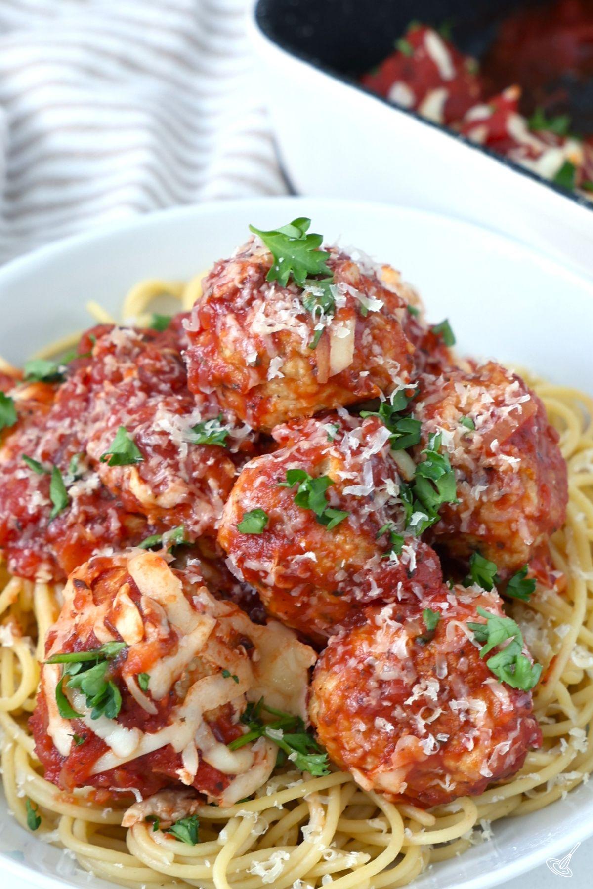 Chicken Parm Meatballs over spaghetti in a serving bowl. 