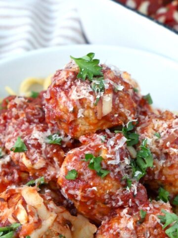 Boulettes de poulet parmesan servies sur des spaghettis dans un bol.