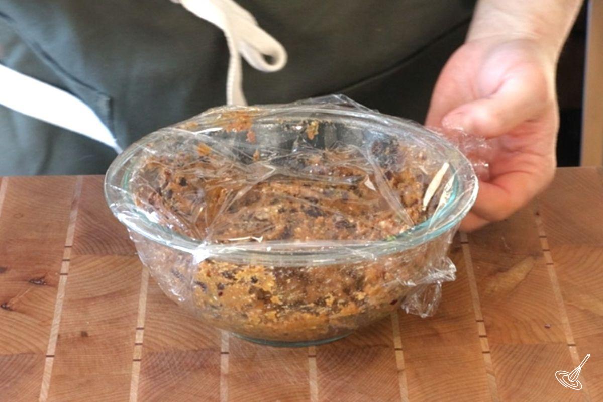 Quelqu'un recouvre le bol contenant le mélange de boulettes de viande avec du film plastique.