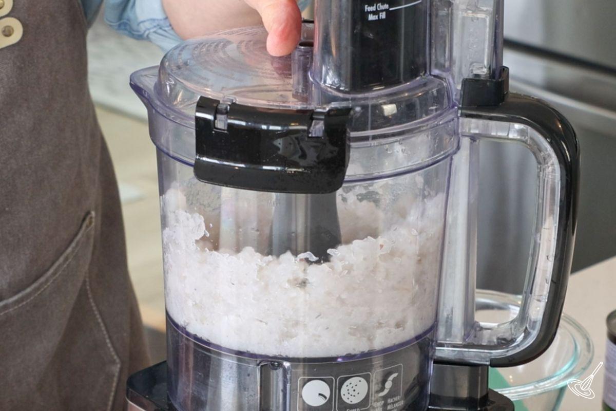 Someone using a food processor to make ground shrimp. 