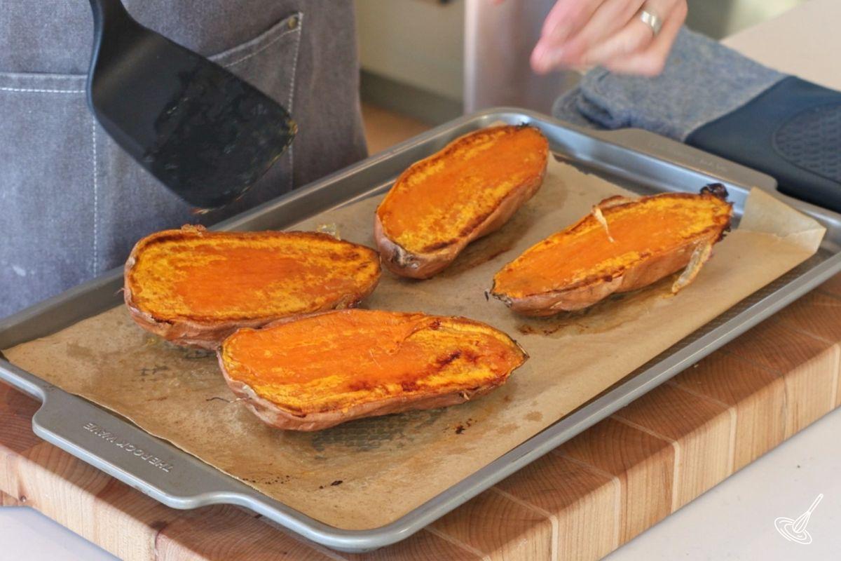Roasted sweet potato halves on a baking tray. 