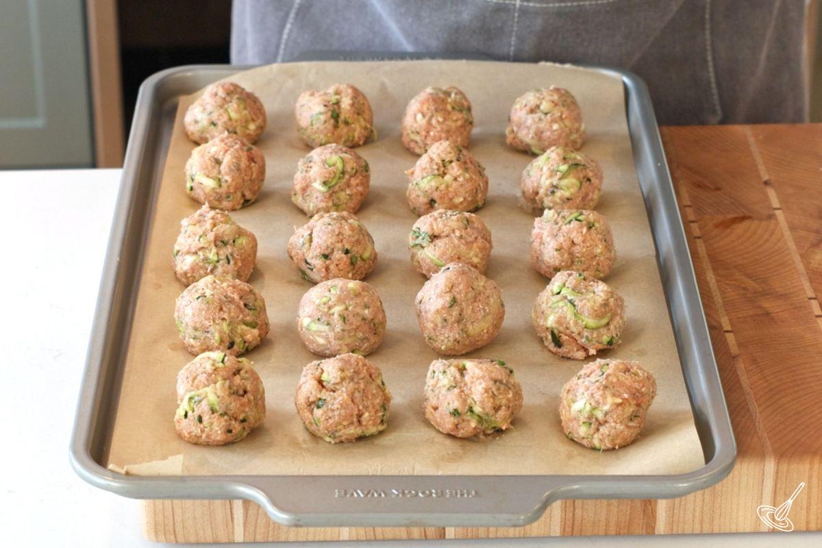 Une plaque de cuisson de boulettes de dinde et de courgette prête à être enfournée.