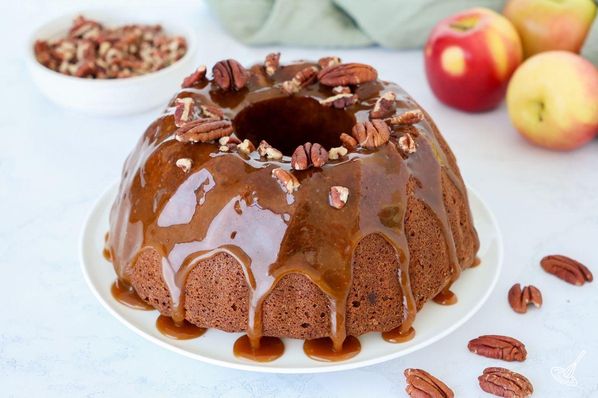 An apple pecan cake with caramel glaze on a plate. 
