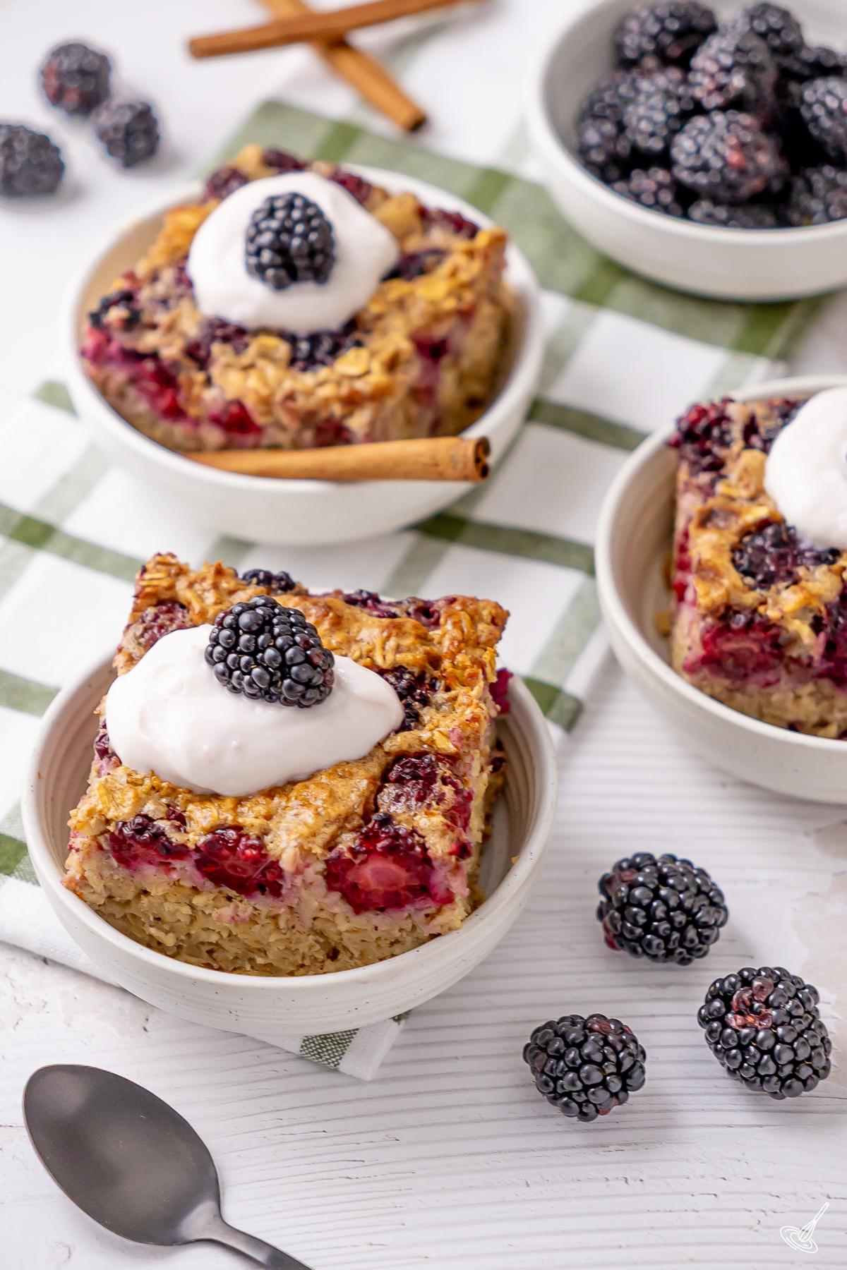 Portions de gruau cuit au four aux mûres, nappées de yogourt. 