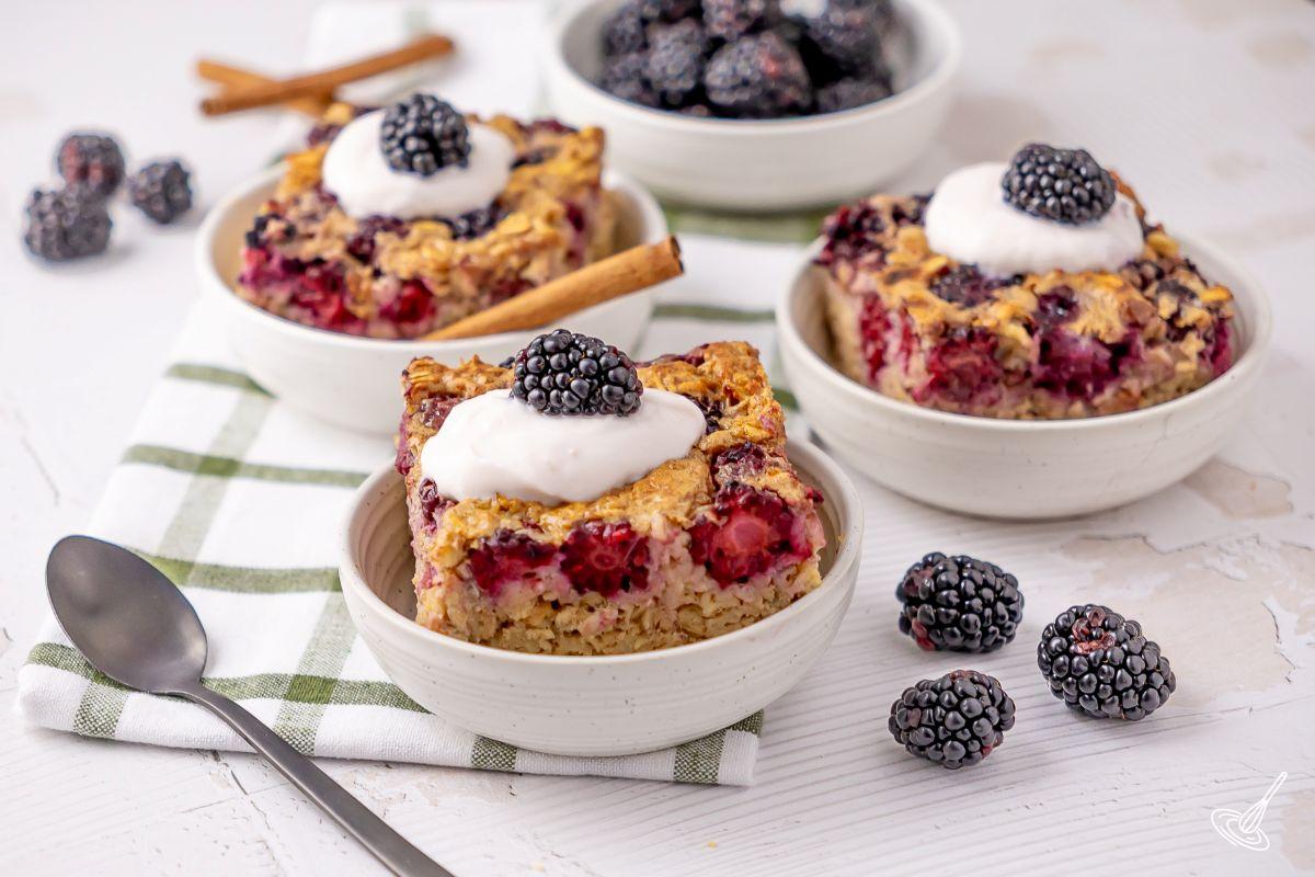 Portions de gruau cuit au four aux mûres, nappées de yogourt.