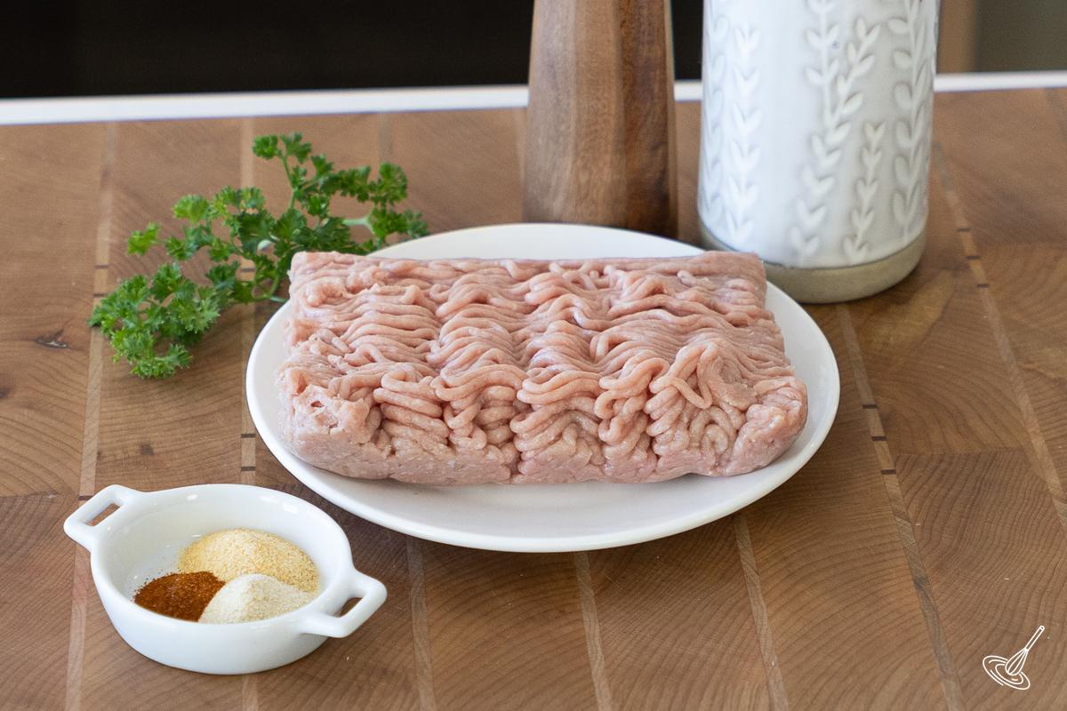 A plate of ground turkey with a dish of spiced beside it. 