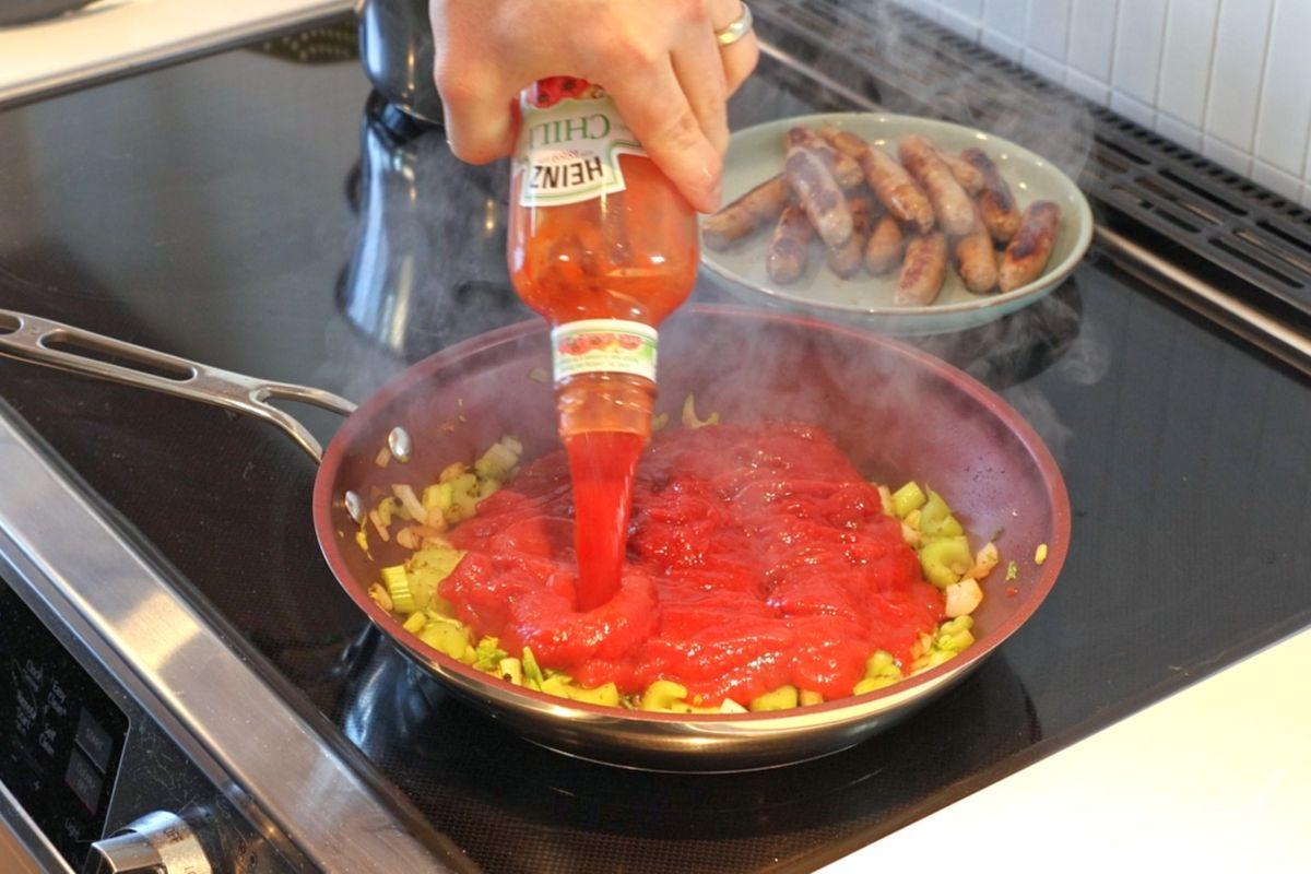 Quelqu'un qui ajoute de la sauce chili à des légumes dans une poêle. 