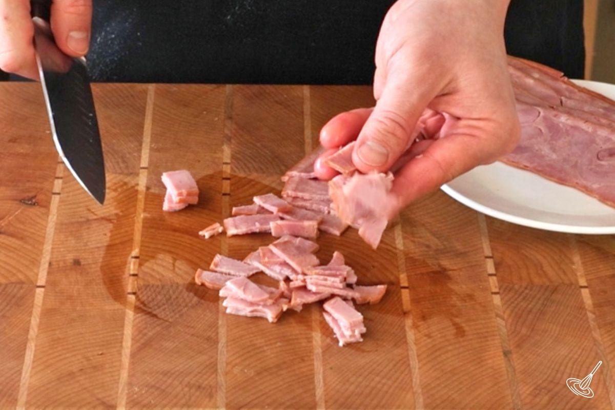 Someone cutting sliced of turkey bacon in small pieces.