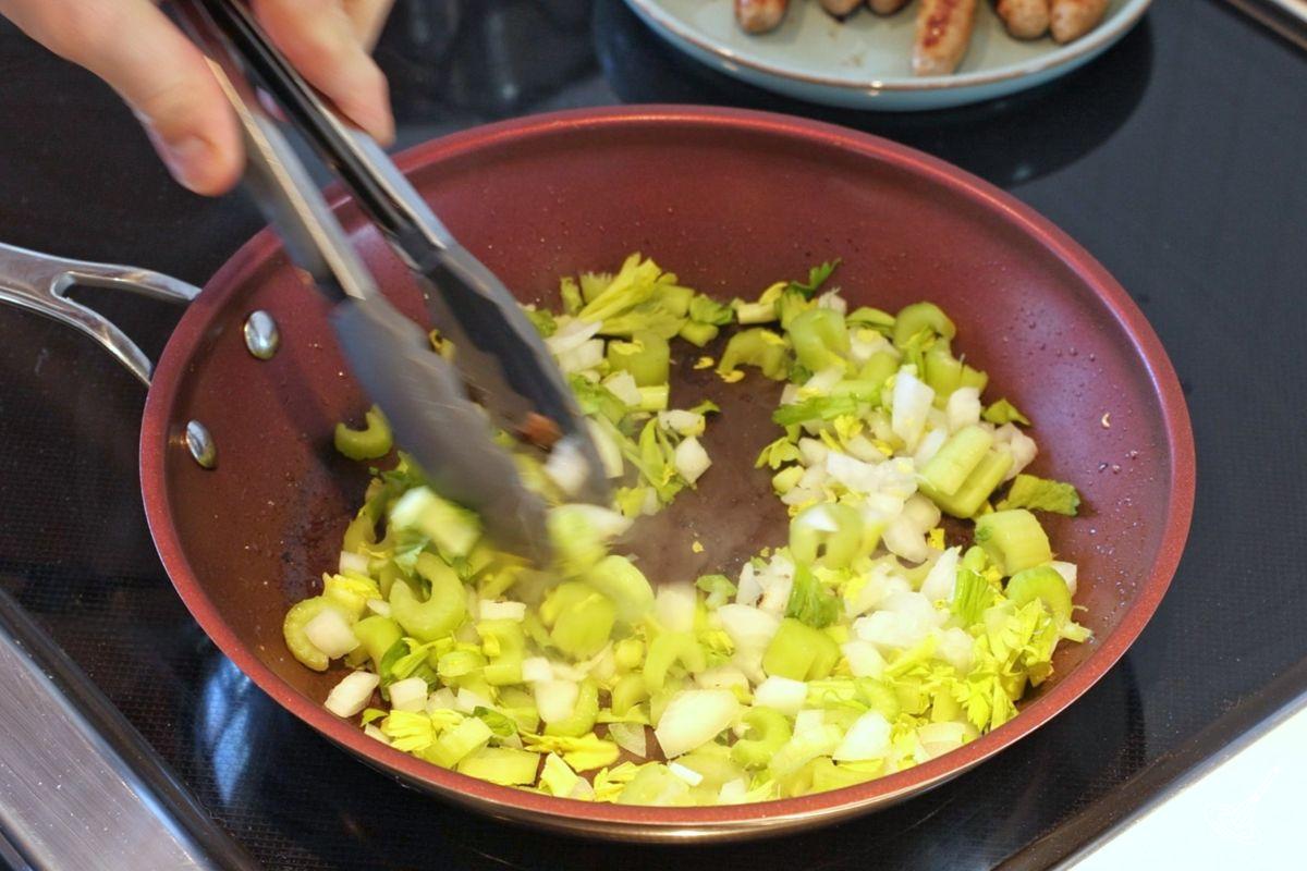 Oignons et céleri émincés en train de cuire dans une poêle. 