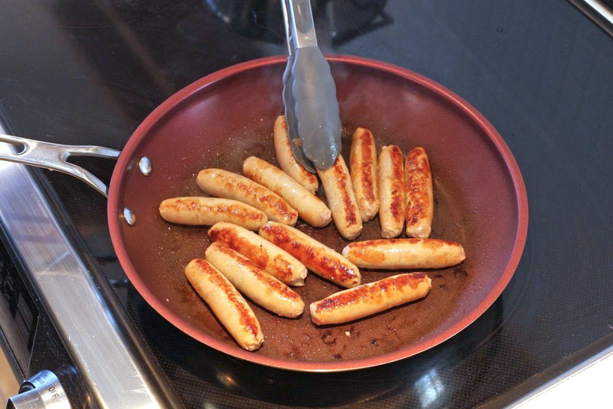 Saucisses de dinde en train de cuire à la poêle.