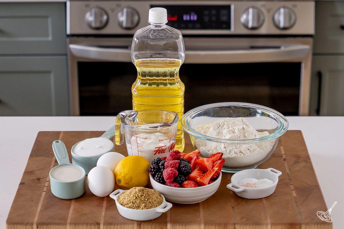Ingrédients disposés sur une planche à découper, comprenant de la farine, des petits fruits, des graines de lin et du yogourt grec.