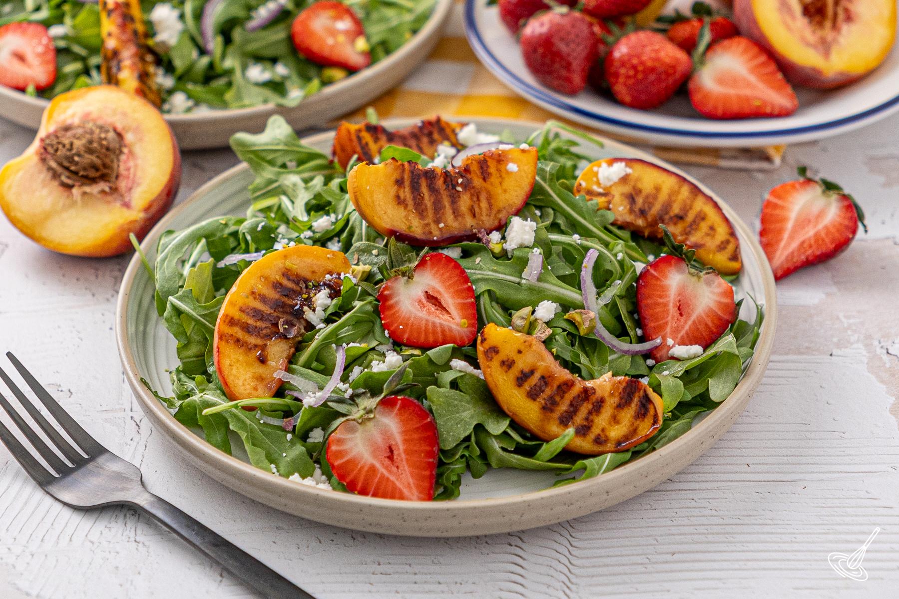 A plate of grilled peach and arugula salad.