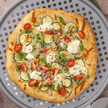 A primavera pizza on a pizza pan.