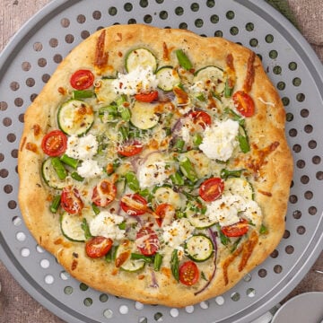 A primavera pizza on a pizza pan.