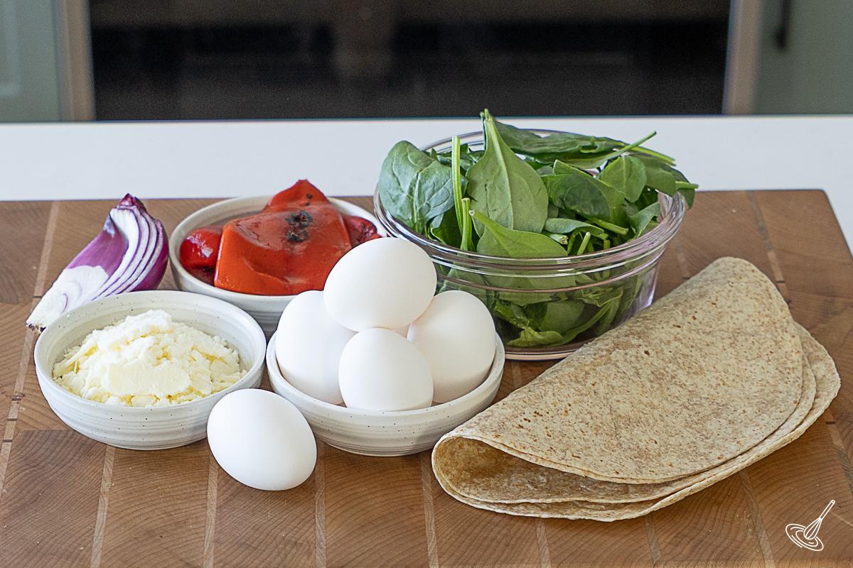Ingredients on a cutting board to make egg white spinach feta wraps. 