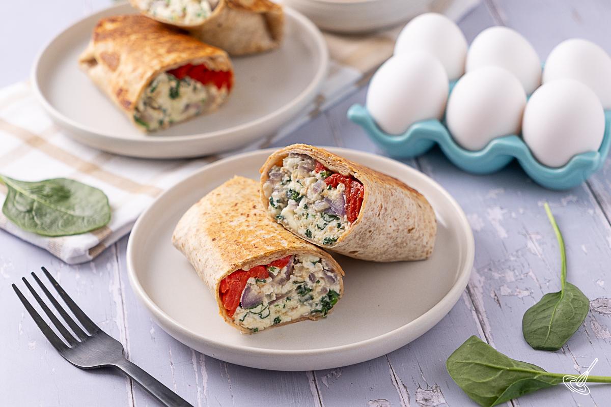 A Spinach Feta Egg White Wrap cut in two on a plate.