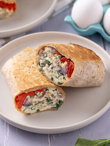A Spinach Feta Egg White Wrap cut in two on a plate.