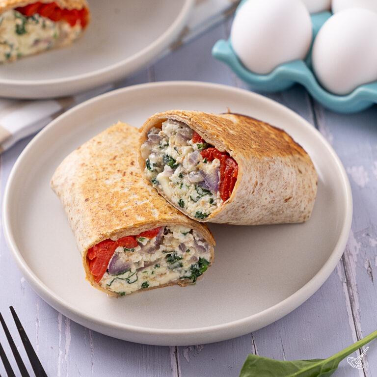 A Spinach Feta Egg White Wrap cut in two on a plate.