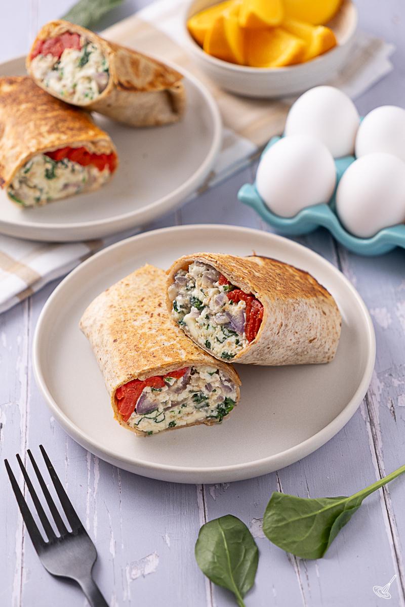 A Spinach Feta Egg White Wrap cut in two on a plate. 