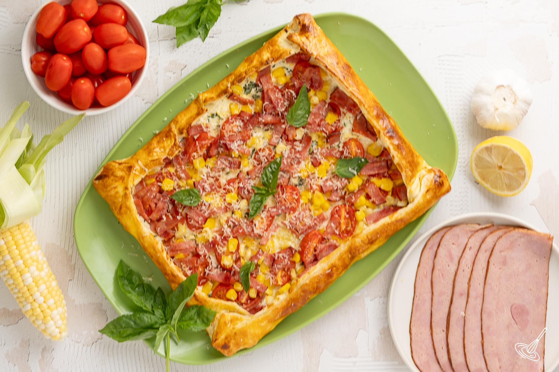 Top view of a whole Sweet Corn, Tomato & Turkey Bacon Galette on a platter.