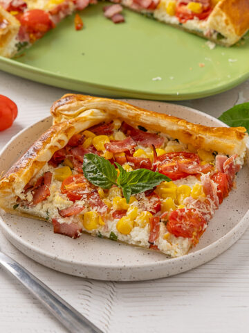 A piece of Sweet Corn, Tomato & Turkey Bacon Galette on a plate.